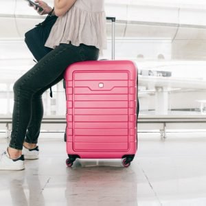 woman-in-white-top-and-denim-jeans-sitting-on-red-luggage-3597111